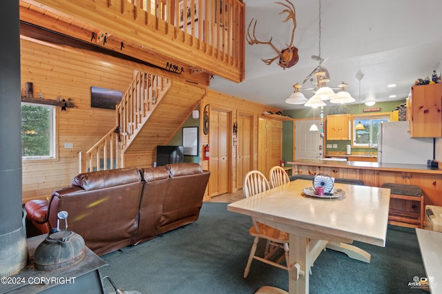 dining space featuring a notable chandelier, wooden walls, and carpet flooring