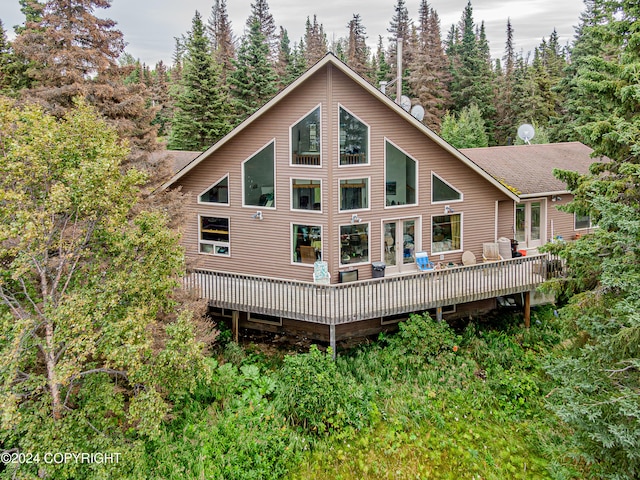 rear view of property featuring a wooden deck, roof with shingles, and a view of trees