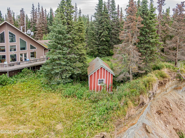 view of yard featuring a forest view, an outbuilding, and a shed