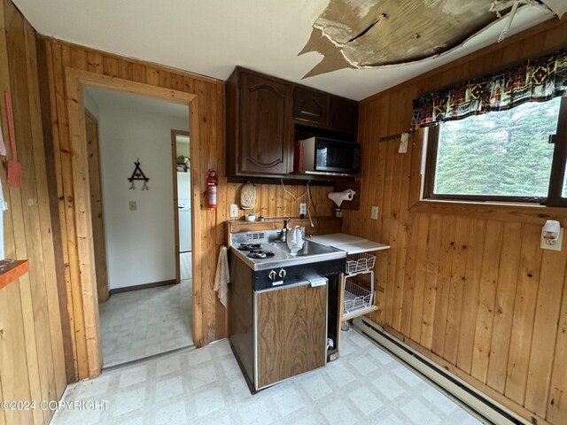 kitchen featuring a baseboard heating unit, black microwave, light floors, light countertops, and wood walls
