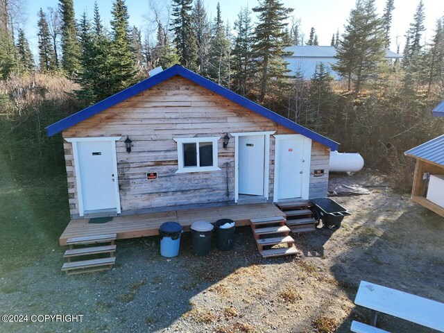 65449 Lingonberry Rd, Ninilchik, AK 99639 - view of front facade with a wooden deck, a view of trees, and heating fuel