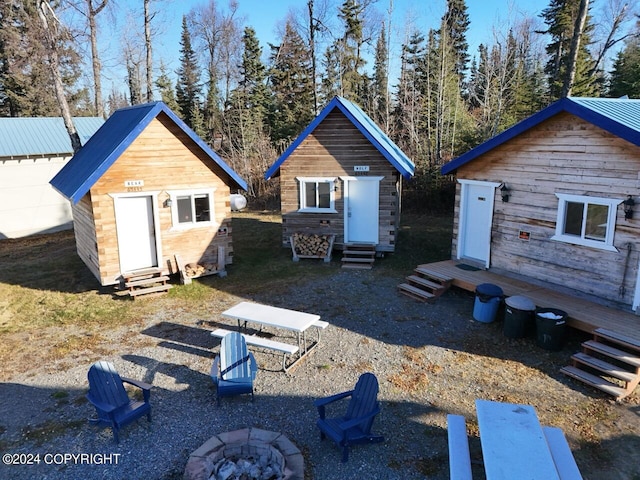 back of property with an outdoor fire pit and a shed