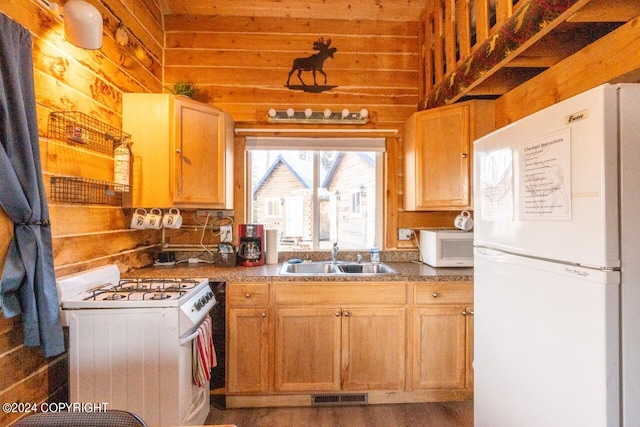 kitchen featuring sink, dark wood-type flooring, white appliances, and wooden walls