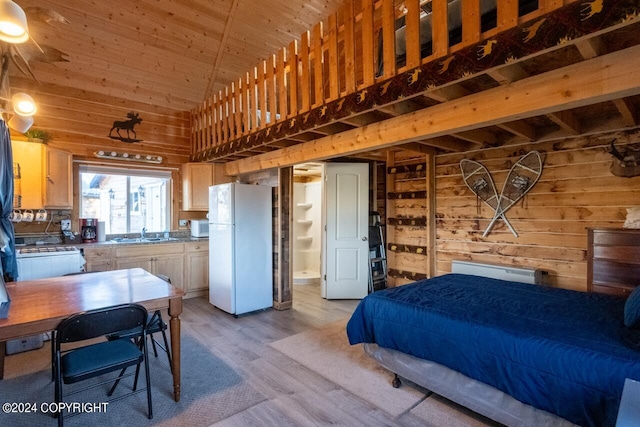 bedroom with light hardwood / wood-style floors, wood walls, and white refrigerator