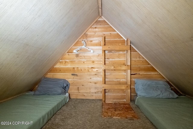 carpeted bedroom with wood walls and vaulted ceiling