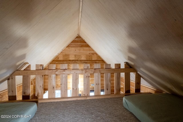 bonus room featuring lofted ceiling, carpet flooring, and wood walls