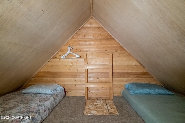 carpeted bedroom with lofted ceiling and wooden walls