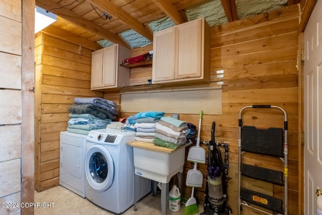 washroom featuring cabinets, wood walls, and washer and clothes dryer