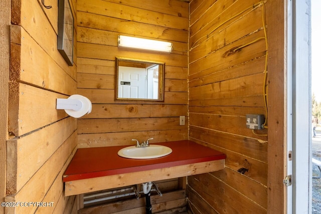 bathroom featuring sink, a healthy amount of sunlight, and wood walls