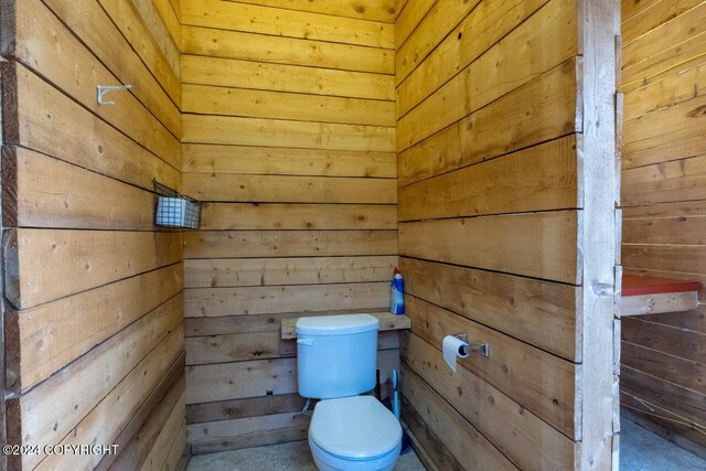 bathroom featuring toilet and wood walls