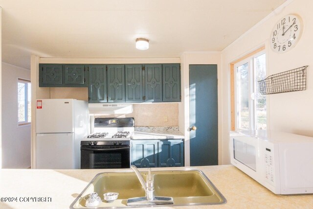 kitchen featuring a healthy amount of sunlight, sink, exhaust hood, and white appliances