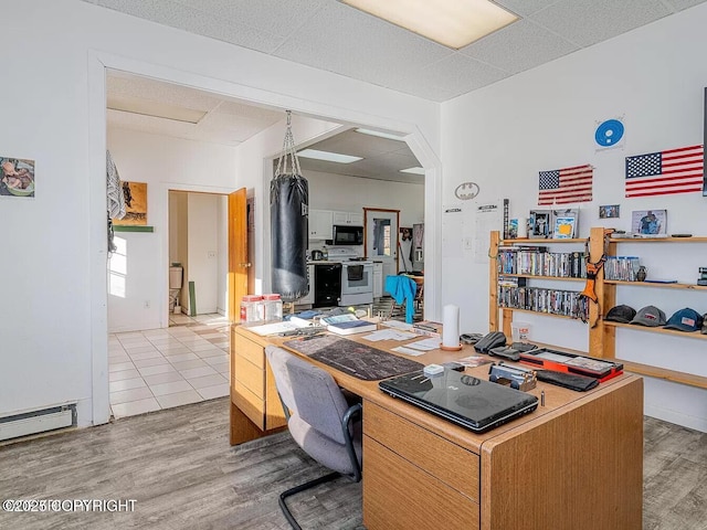 office area featuring arched walkways, a baseboard heating unit, and wood finished floors