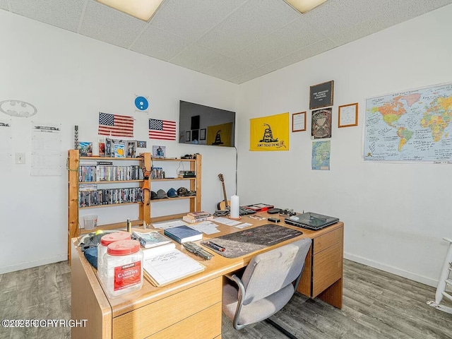 office space featuring a paneled ceiling, baseboards, and wood finished floors