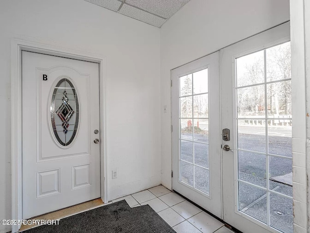 entryway with french doors, a drop ceiling, and light tile patterned floors