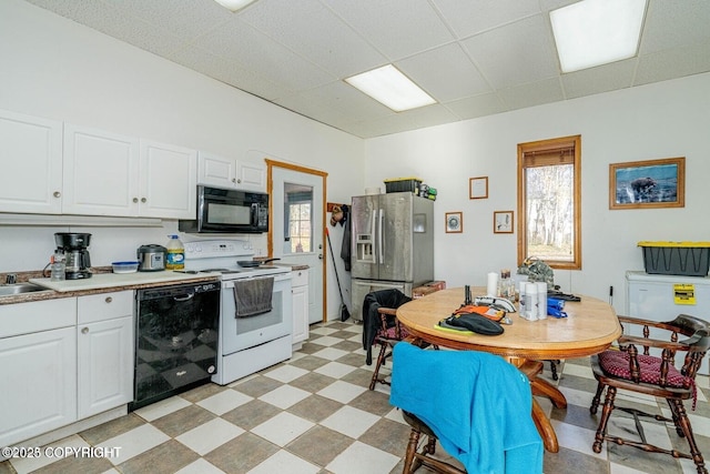 kitchen featuring a paneled ceiling, light floors, white cabinetry, black appliances, and light countertops