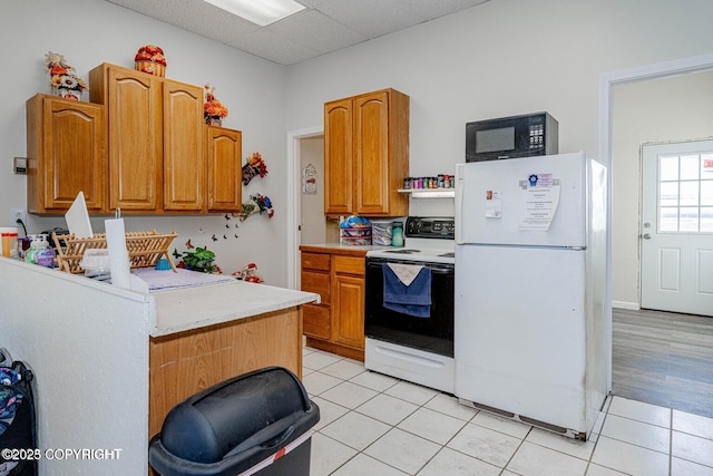 kitchen featuring light countertops, black microwave, freestanding refrigerator, and range with electric cooktop