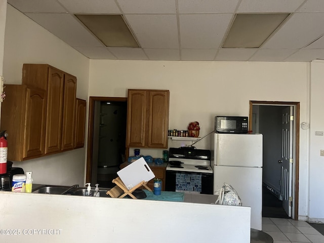 kitchen featuring a paneled ceiling, freestanding refrigerator, black microwave, electric stove, and brown cabinets