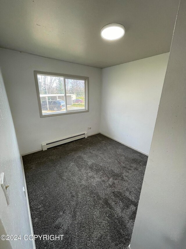 empty room featuring baseboard heating and carpet