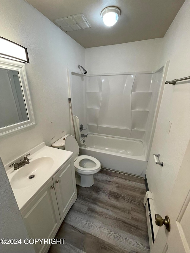 full bathroom featuring toilet, bathtub / shower combination, a baseboard heating unit, hardwood / wood-style floors, and vanity