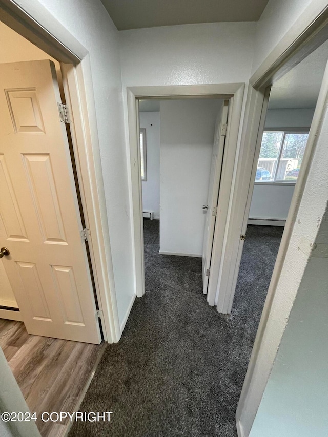 corridor with a baseboard radiator and dark carpet