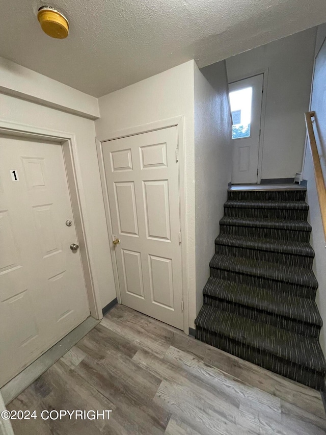 stairs featuring a textured ceiling and hardwood / wood-style flooring