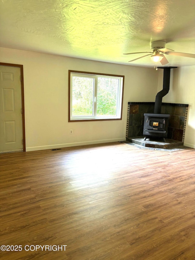7025 S Gilleys Cir, Wasilla, AK 99654 - unfurnished living room with a wood stove, wood finished floors, and ceiling fan