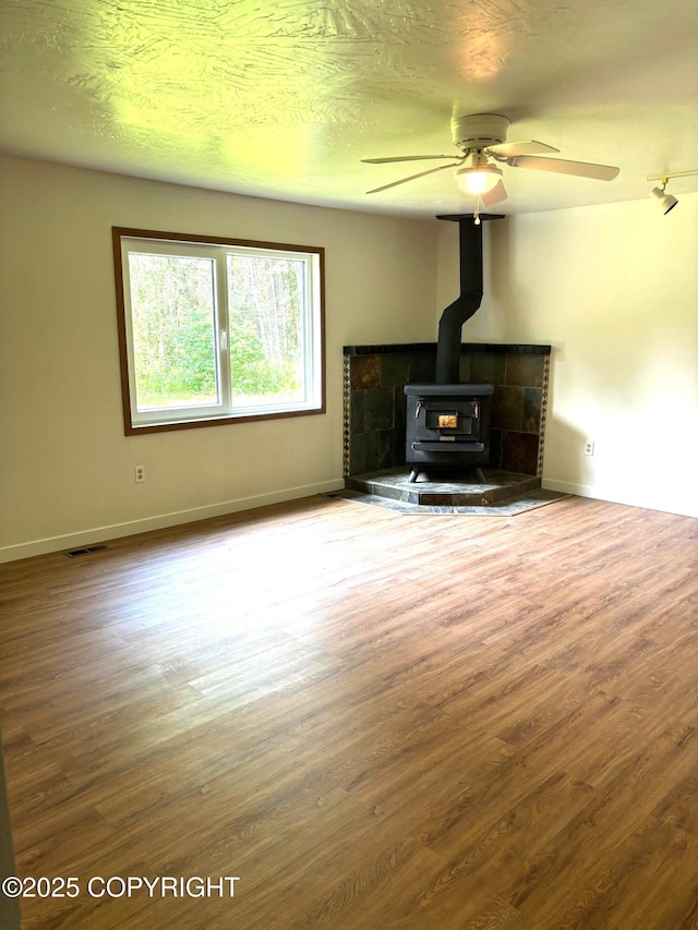 7025 S Gilleys Cir, Wasilla, AK 99654 - unfurnished living room with a wood stove, wood finished floors, and ceiling fan