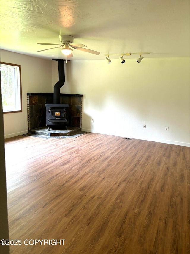 7025 S Gilleys Cir, Wasilla, AK 99654 - unfurnished living room featuring a wood stove, wood finished floors, and a ceiling fan