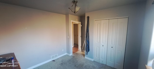 unfurnished bedroom with a closet and light colored carpet