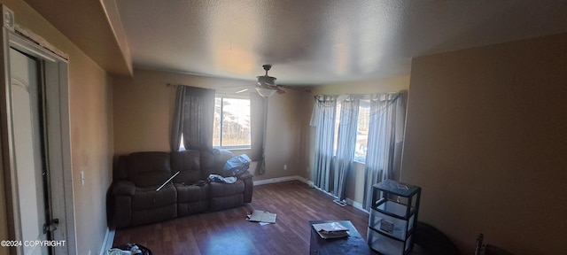 living room featuring a textured ceiling, ceiling fan, and dark hardwood / wood-style flooring