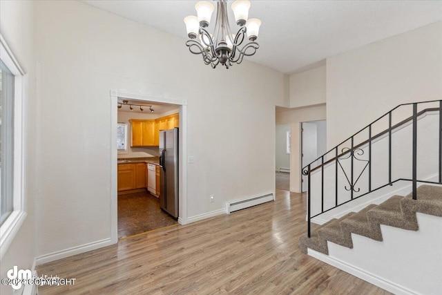 interior space featuring baseboard heating, a chandelier, and light hardwood / wood-style flooring