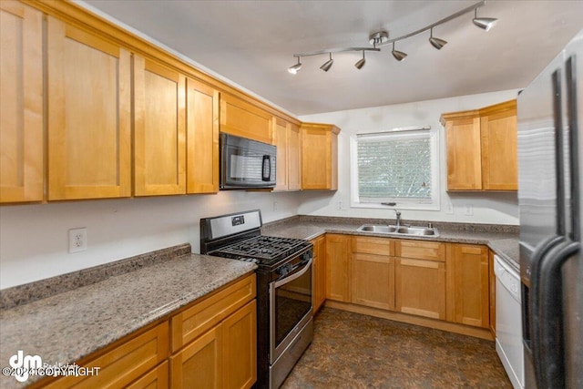 kitchen with stainless steel appliances, sink, light stone counters, and rail lighting