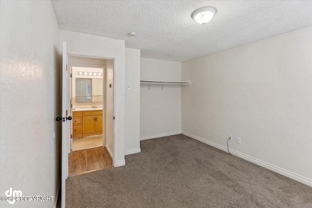 unfurnished bedroom featuring sink, a textured ceiling, carpet flooring, and a closet