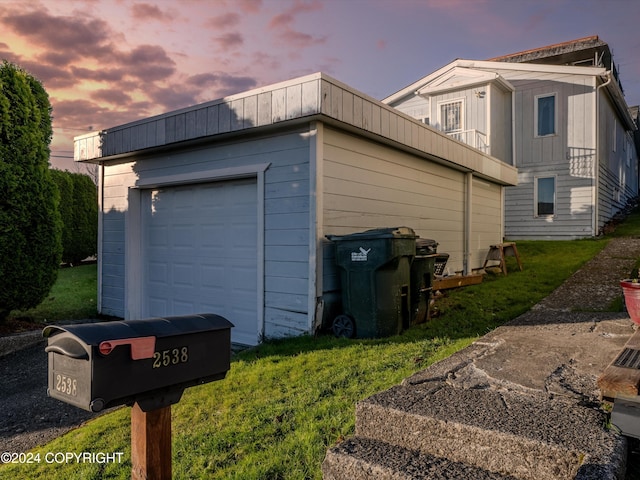 garage at dusk featuring a yard