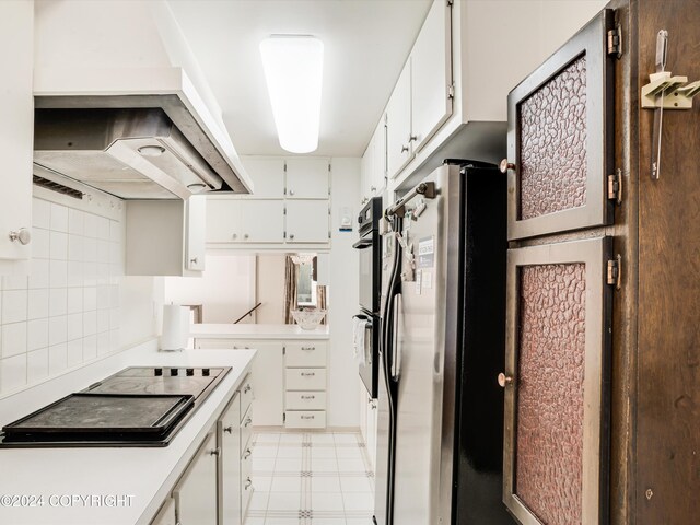 kitchen featuring ventilation hood, tasteful backsplash, white cabinetry, and stainless steel refrigerator