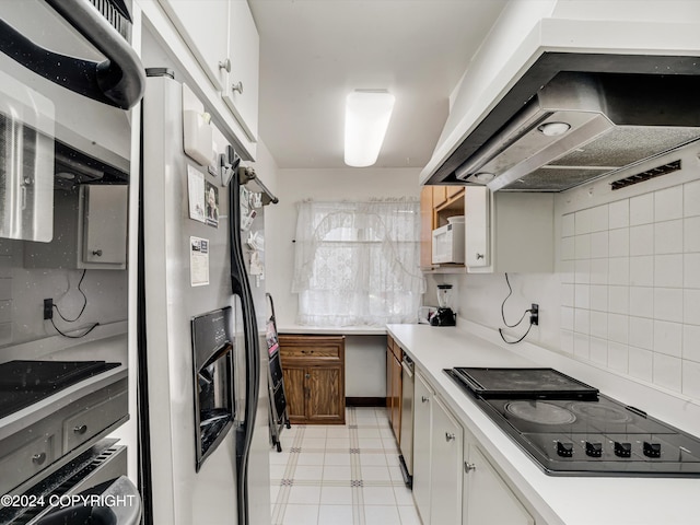 kitchen featuring tasteful backsplash, wall chimney exhaust hood, white cabinets, and appliances with stainless steel finishes