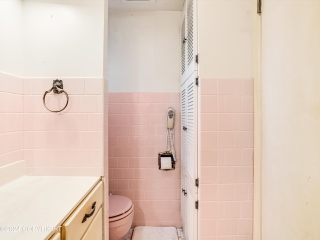 bathroom featuring vanity, toilet, and tile walls