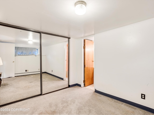 basement featuring light carpet and a baseboard heating unit