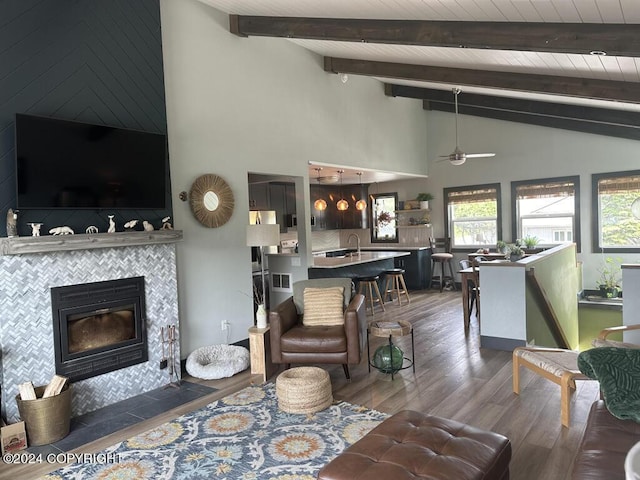 living room featuring wood ceiling, ceiling fan, wood-type flooring, high vaulted ceiling, and a tiled fireplace