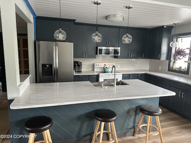 kitchen featuring hanging light fixtures, a breakfast bar area, hardwood / wood-style flooring, light stone countertops, and stainless steel appliances