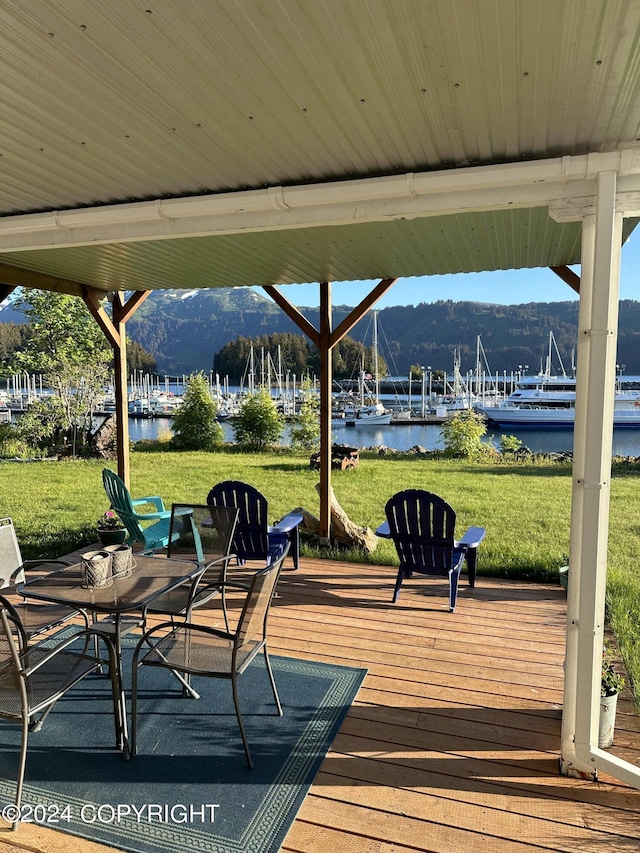 wooden terrace with a water and mountain view and a lawn