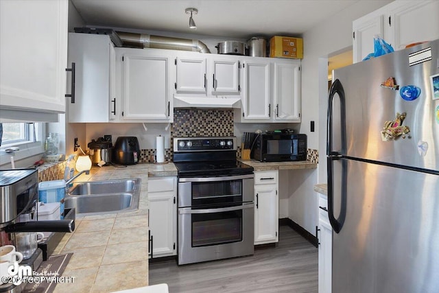 3591 Lynn Dr # 1, Anchorage, AK 99508 - kitchen with appliances with stainless steel finishes, tile countertops, a sink, white cabinetry, and ventilation hood