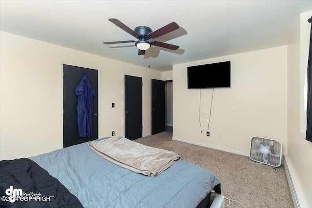 carpeted bedroom featuring a walk in closet, a textured ceiling, and ceiling fan