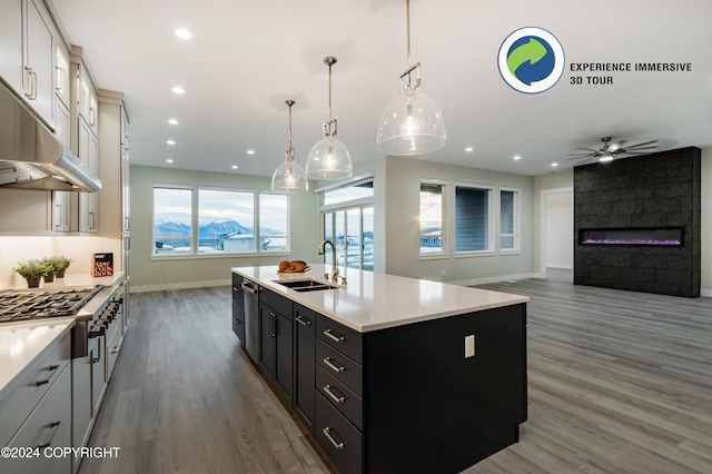 kitchen featuring a center island with sink, white cabinetry, decorative light fixtures, dark hardwood / wood-style floors, and sink