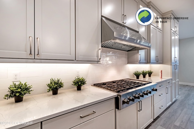 kitchen with tasteful backsplash, gray cabinetry, light stone countertops, light hardwood / wood-style floors, and stainless steel gas cooktop