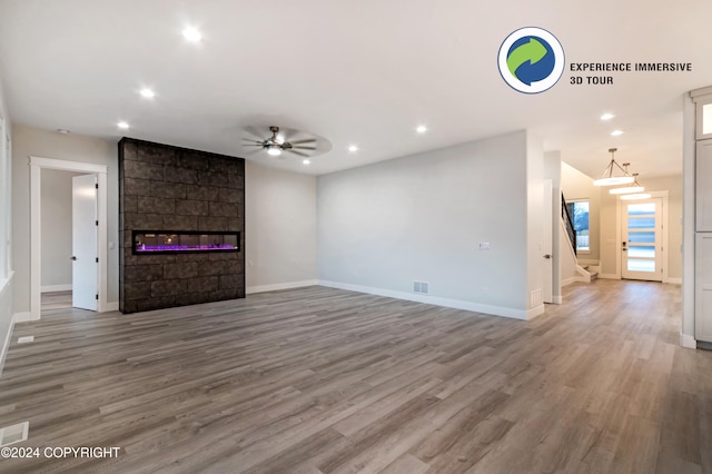 unfurnished living room with hardwood / wood-style flooring, ceiling fan, and a fireplace