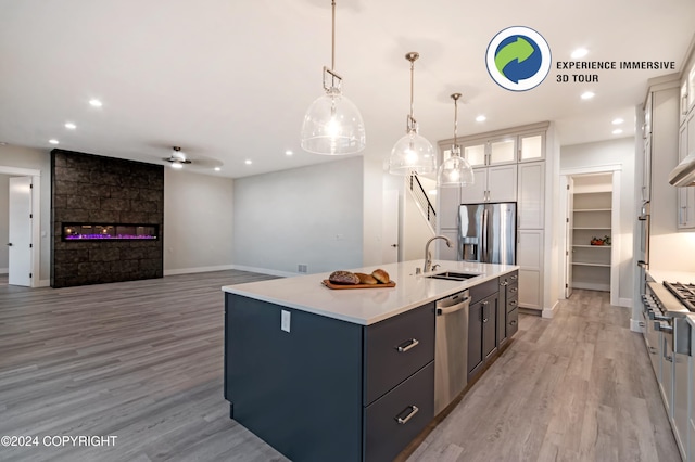 kitchen with light hardwood / wood-style flooring, sink, a kitchen island with sink, white cabinetry, and appliances with stainless steel finishes