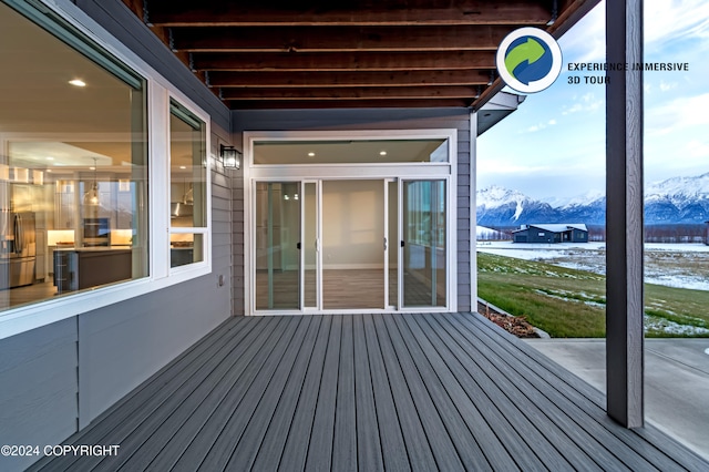 snow covered deck featuring a mountain view and a patio