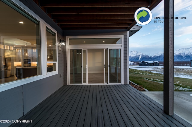 snow covered deck with a patio and a mountain view