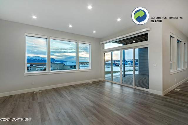 unfurnished room with hardwood / wood-style flooring and a mountain view